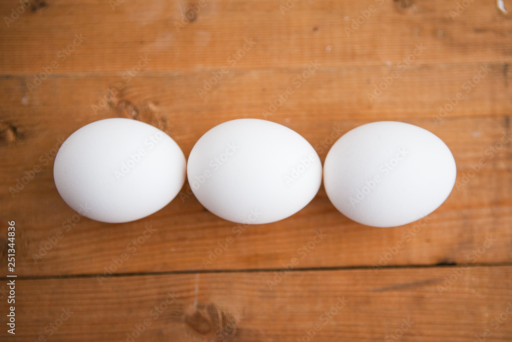 Three white eggs on a wood ground