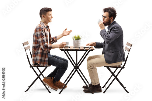 Young guy in a cafe talking to a bearded man drinking coffee