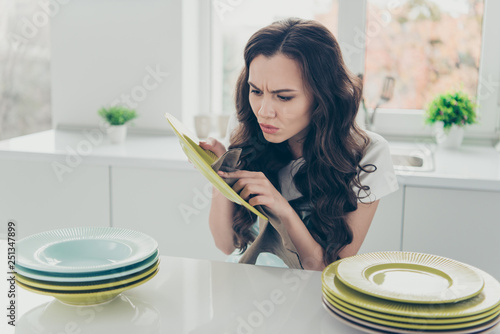 Portrait of her she nice cute beautiful concentrated unsatisfied wavy-haired house-wife polishing plates piles on table in modern light white interior indoors photo