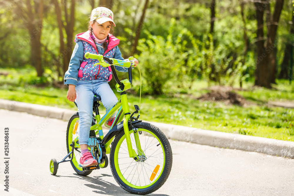 Child on a bicycle at asphalt road in summer. Bike in the park Child on a bicycle at asphalt road in summer. Bike in the park