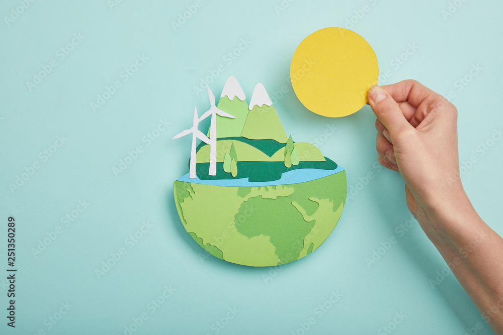 Φωτογραφία top view of woman holding paper cut sun and planet with renewable energy sources