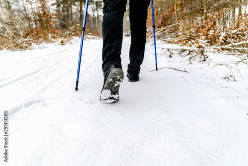 Woman hiking in snow. Boots and legs detail. Outdoor activity, winter walk in snow with nordic walking sticks. © alicja neumiler