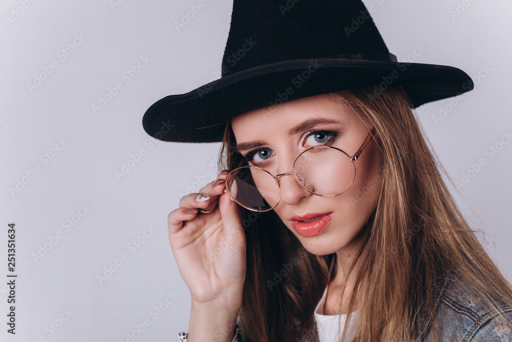 Close up portrait of young gorgeous beauty student girl in black hat on grey background looking at camera Close up portrait of young gorgeous beauty student girl in black hat on grey background looking at camera