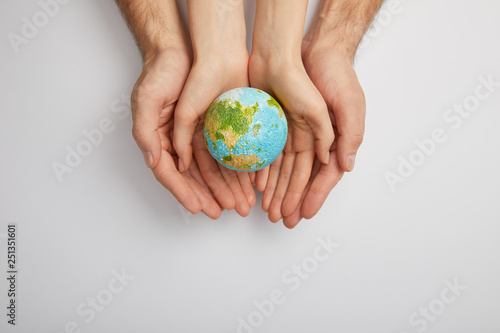 top view of man and woman holding planet model on grey background, earth day concept