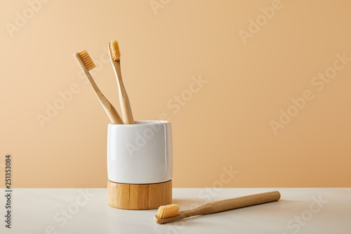 bamboo toothbrushes and holder on white table and beige background photo