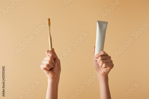 Quadro su tela cropped view of woman holding bamboo brown toothbrush and toothpaste in tube on