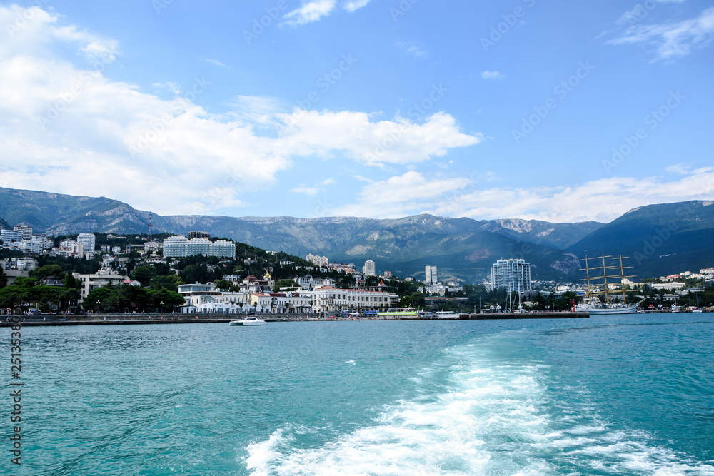 The yacht sails into the sea, the waves from the ship. Mountain View. Seafront seaside resort. 
