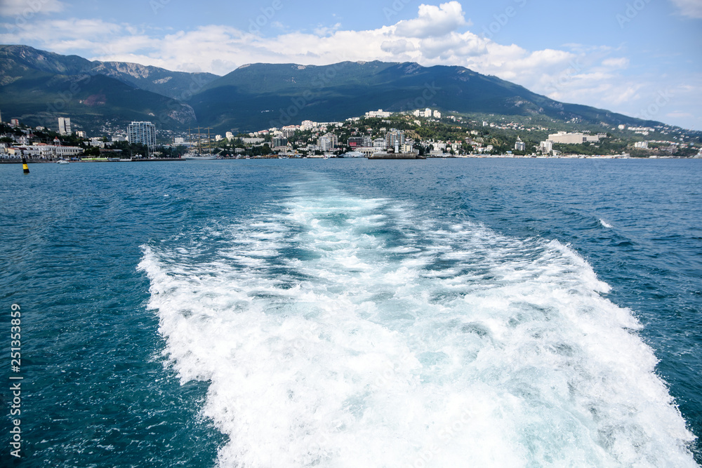 The yacht sails into the sea, the waves from the ship. Mountain View. Seafront seaside resort. The yacht sails into the sea, the waves from the ship. Mountain View. Seafront seaside resort.