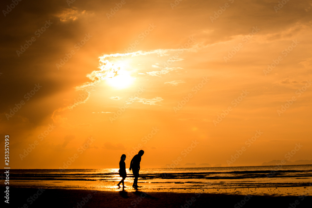 Girls playing on the sand at sunset. Silhouette of buddy girls on the beach, in holiday travel with sunday's over sky