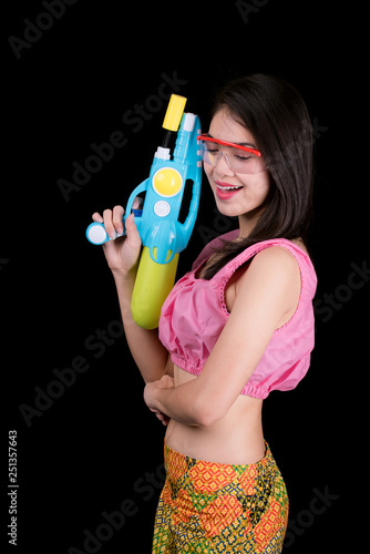 Portrait cheerful young asian woman with waterproof glasses holding plastic water gun on black background. Songkran festival, Thailand. Thai New Year's Day.