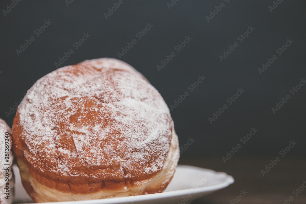 delicious donuts sprinkled with powdered sugar with filling on a dark background delicious donuts sprinkled with powdered sugar with filling on a dark background