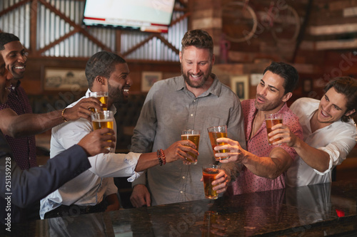 Group Of Male Friends On Night Out For Bachelor Party In Bar Making Toast Together photo