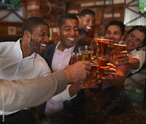 Group Of Male Friends On Night Out For Bachelor Party In Bar Making Toast Together