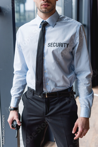 partial view of handsome guard in suit holding walkie-talkie photo