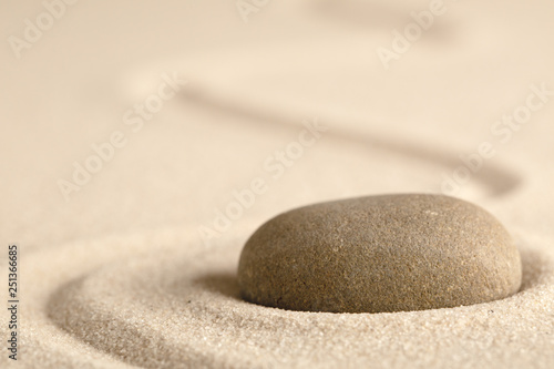 Zen meditation stone with raked line in sand. Concept for harmony relaxation and purity.