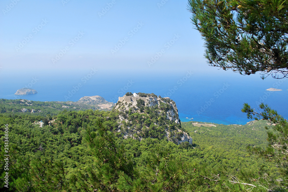 View of the mountain with the ruins of Monolitos Castle against the background of the sea and sky, the island of Rhodes, Greece