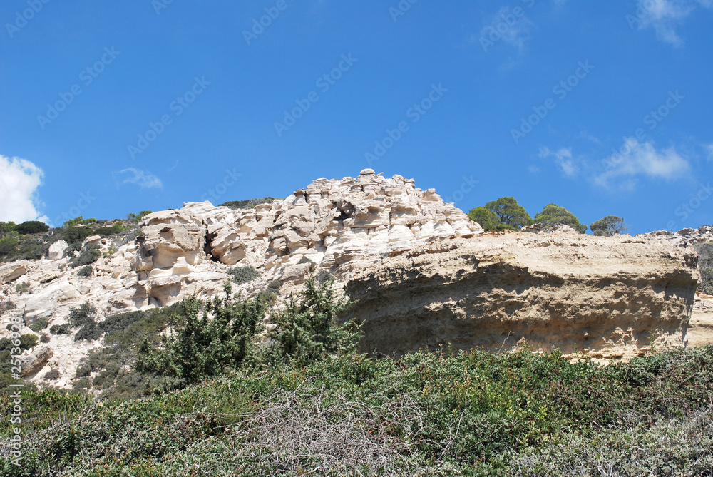 Large white stones among green plants against the blue sky, Cape Fourny, Rhodes Island, Greece