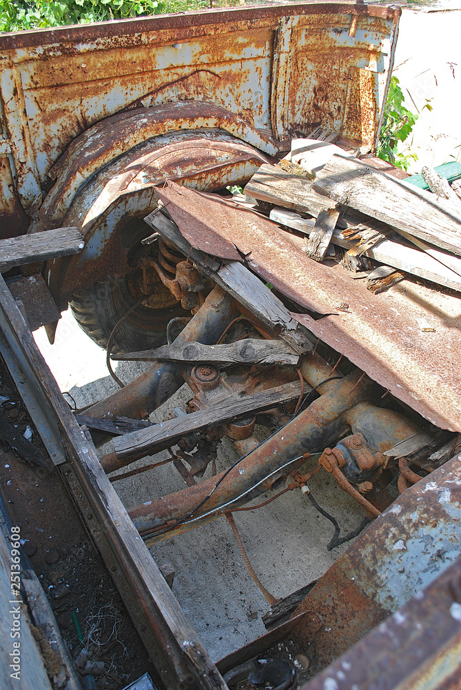 Close-up of transmission and remnants of a wooden body of an old rusty pickup truck, Rhodes Island, Greece