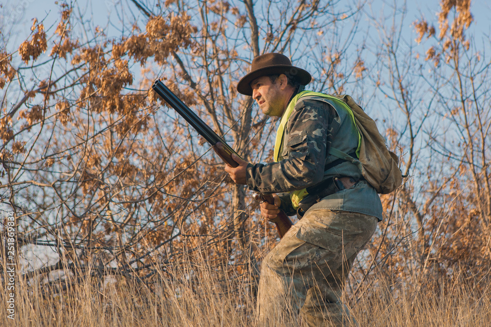 Hunter with a gun and a dog go on the first snow in the steppe, Hunting pheasant in a reflective vest	