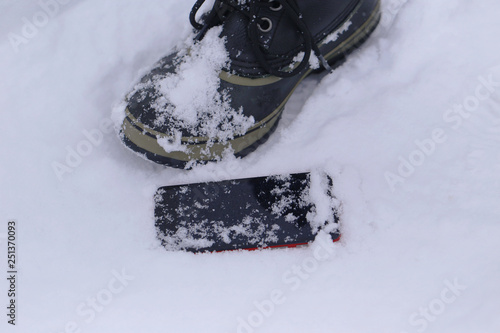 足元の雪の上に落としたスマートフォン