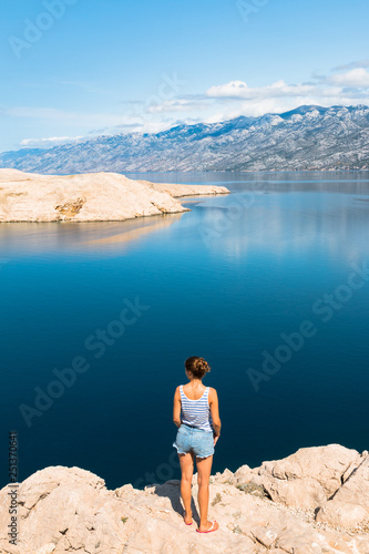 Junge Frau schaut auf eine Landschaft von Berge und Meer in Kroatien, Pag