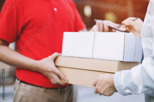 parcel delivery man of a package through a service. and close up hand customer female accepting a delivery of boxes from delivery man postal send direct to home.