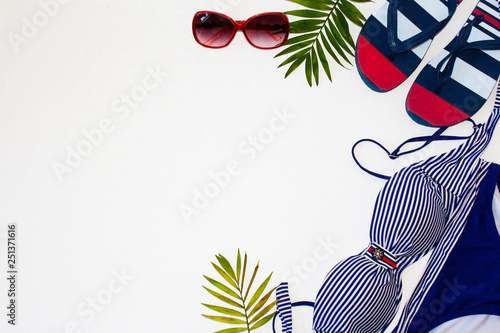 Flat lay summer beach holiday accesorries on white background with palm leaf, camera, straw hatand and sunglasses.Space for text. Travel and beach vacation, top view.Overhead view of woman's swimwear. photo