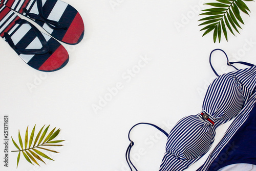 Flat lay summer beach holiday accesorries on white background with palm leaf, camera, straw hatand and sunglasses.Space for text. Travel and beach vacation, top view.Overhead view of woman's swimwear. photo