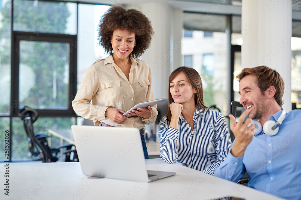Colleagues looking at laptop and helping each other to solve a problem. Office interior. Colleagues looking at laptop and helping each other to solve a problem. Office interior.