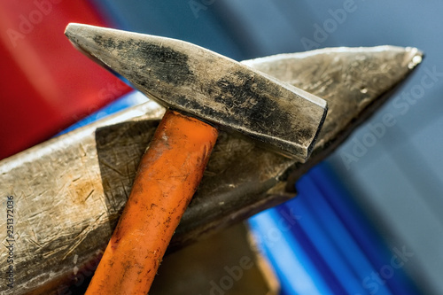 Hammer on a metal anvil in a workshop. Close-up of metalworking tools.