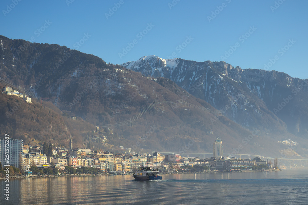 Montreux, Switzerland - 02 17, 2019: Ship cruising towards Montreux with mountains in the background.