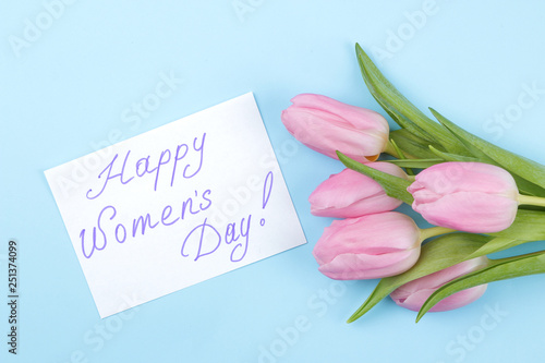 A bouquet of beautiful pink flowers of tulips on a trendy bright blue background. Spring. holidays. text happy women's day. top view.