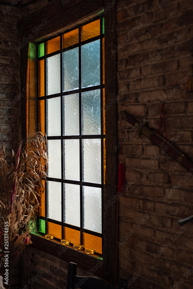 Antique window with colors on a brick wall with some dried ornamental plants Antique window with colors on a brick wall with some dried ornamental plants