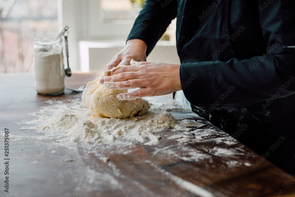 Fototapeta premium Female chef kneading dough in the kitchen
