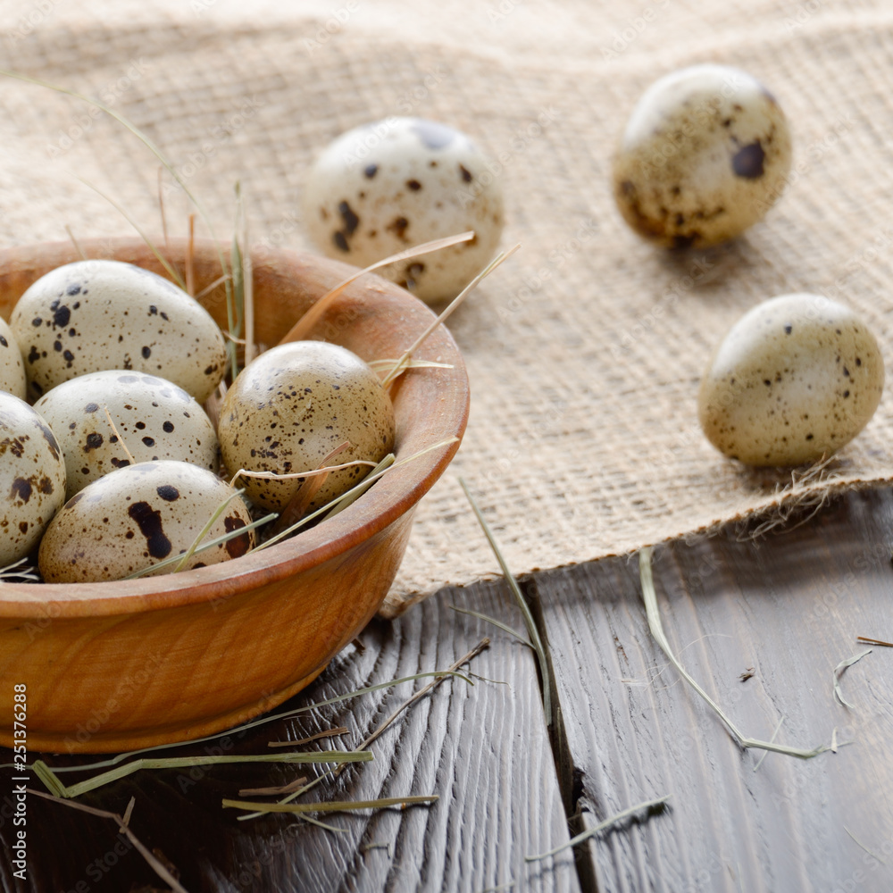 Fresh organic quail eggs in wooden bowl on rustic kitchen table. Space for text Fresh organic quail eggs in wooden bowl on rustic kitchen table. Space for text