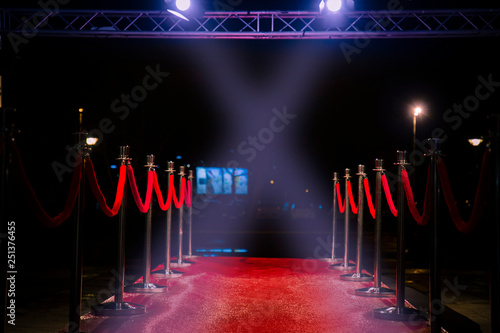 Red carpet with  barriers, velvet ropes and lights in the background