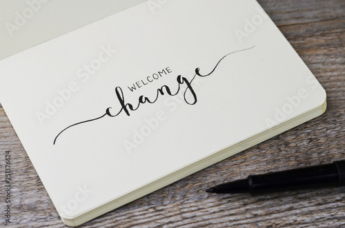 WELCOME CHANGE hand lettering in notebook with pen on wooden background photo
