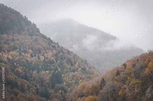 Clouds rolling through autumn mountains on dark and moody day. Vosges, France
