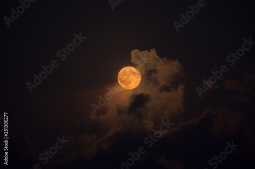 Pleine lune rousse au milieu des nuages de nuit photo
