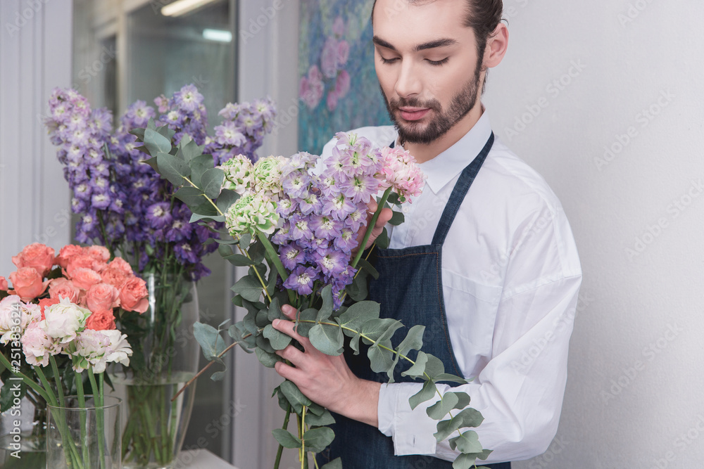 Small business. Male florist in flower shop. Floral design studio, making decorations and arrangements. Flowers delivery, creating order. The man in female profession. Gender equality concept
