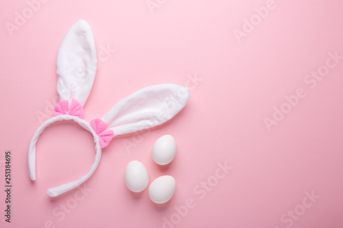 White rabbit bunny ears and eggs on pink background. Symbol Happy Easter Flat lay