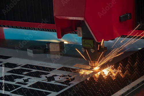 The CNC fiber laser cutting machine cutting the metal plate with the sparking light. The sheet metal working operation.