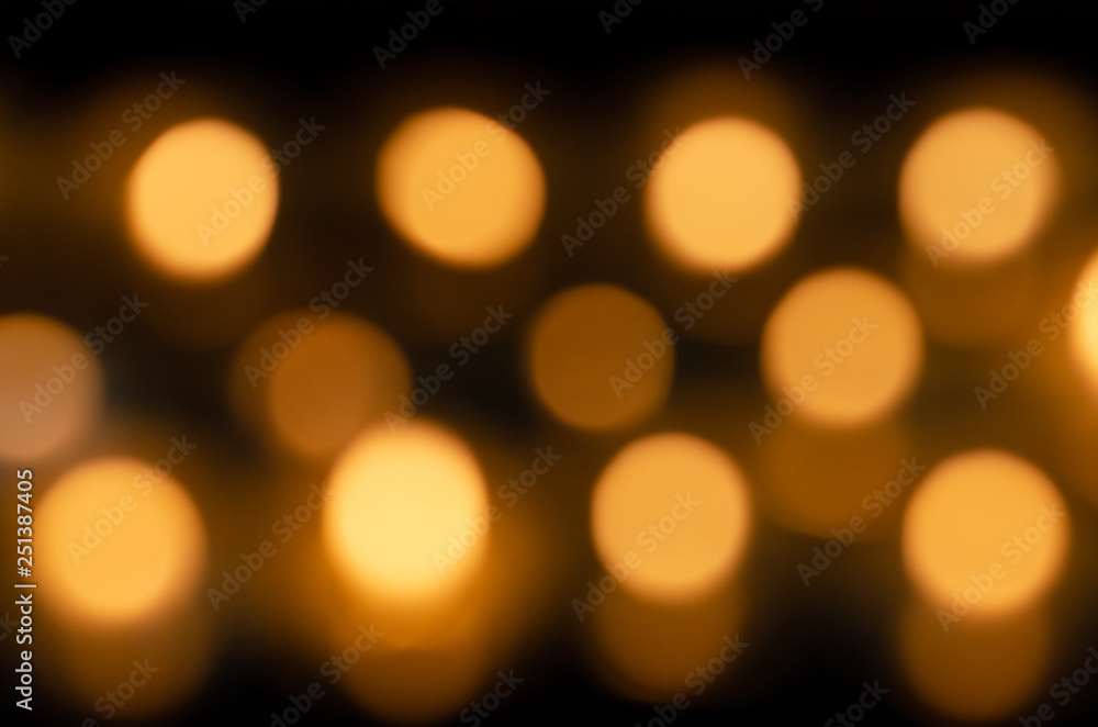 Fototapeta premium Many beautiful lit candles in a row glowing with a golden yellow light - selective focus