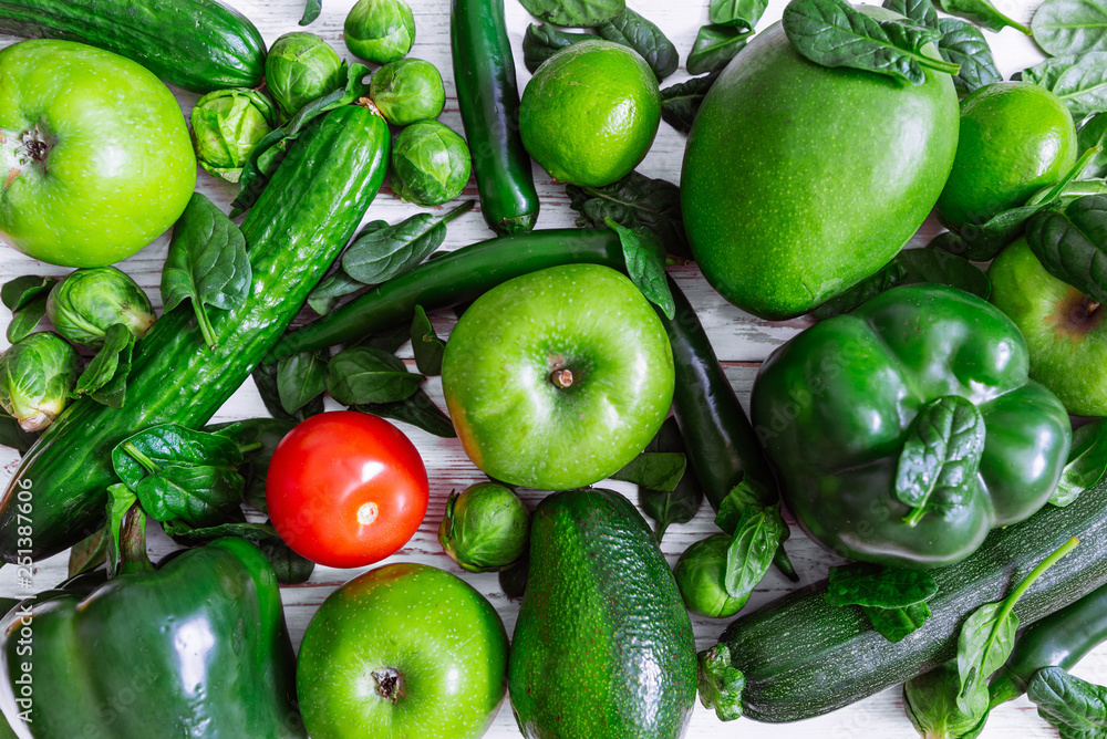 be different concept. red tomato surrounded by green fruits and vegetables. overhead view be different concept. red tomato surrounded by green fruits and vegetables. overhead view