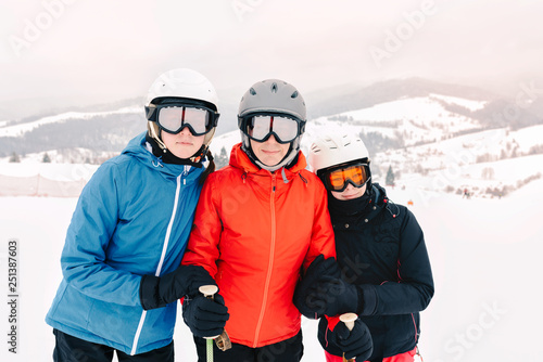 Happy family in winter clothing at the ski resort - skiing, winter, snow, fun - mom and daughters enjoying winter vacations