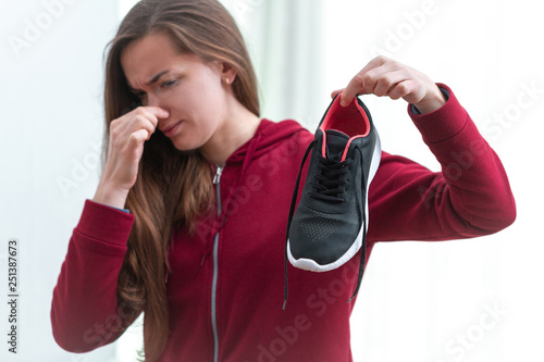 Foto Woman is feeling unpleasant smell from sweaty running shoes after long sport training and active lifestyle