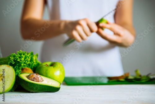 green fruits on front. woman cut fruits on background. healthy food concept