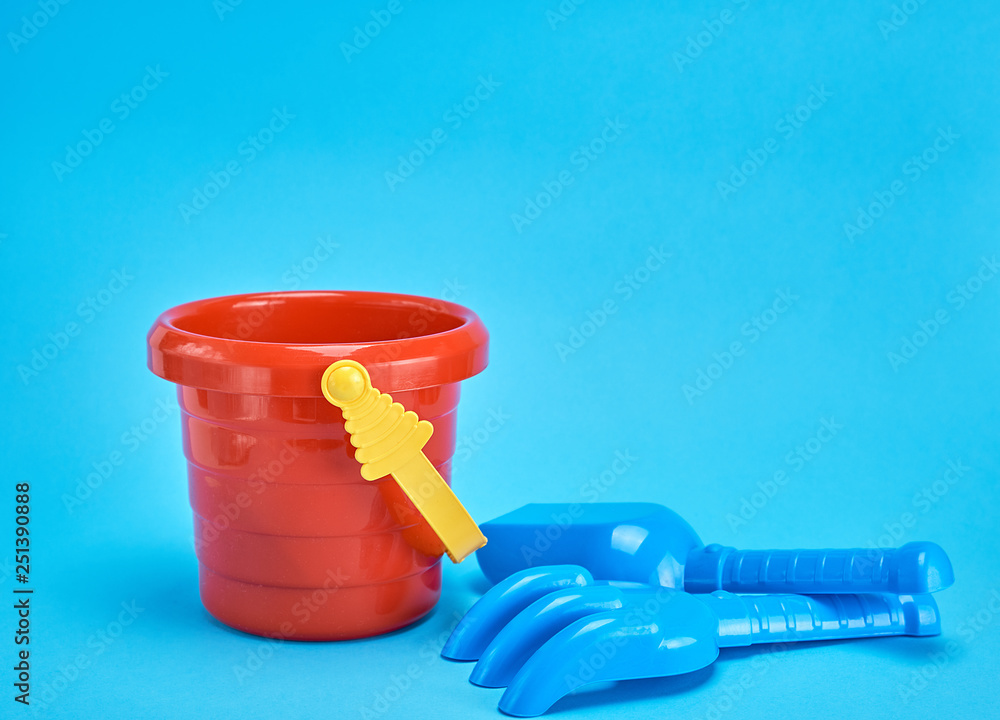 empty baby plastic red bucket and shovel with a rake