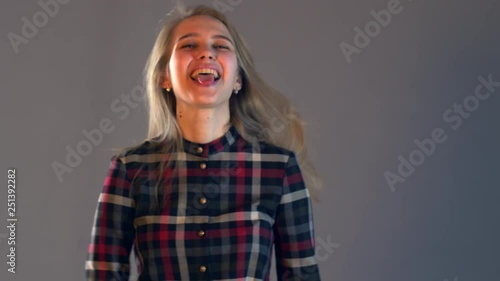 Young blonde girl in plaid dress with beautiful hair and full lips reads messages on smartphone. Woman changes in face showing her emotions. Simple beauty. Tender emotions and coquetry