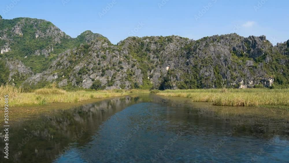 Scenic view of beautiful karst scenery, wetlands seen from the boat at Van Long Nature Reserve, Vietnam. Tourists traveling in small boat in tranquil landscape. Scenic view of beautiful karst scenery, wetlands seen from the boat at Van Long Nature Reserve, Vietnam. Tourists traveling in small boat in tranquil landscape.